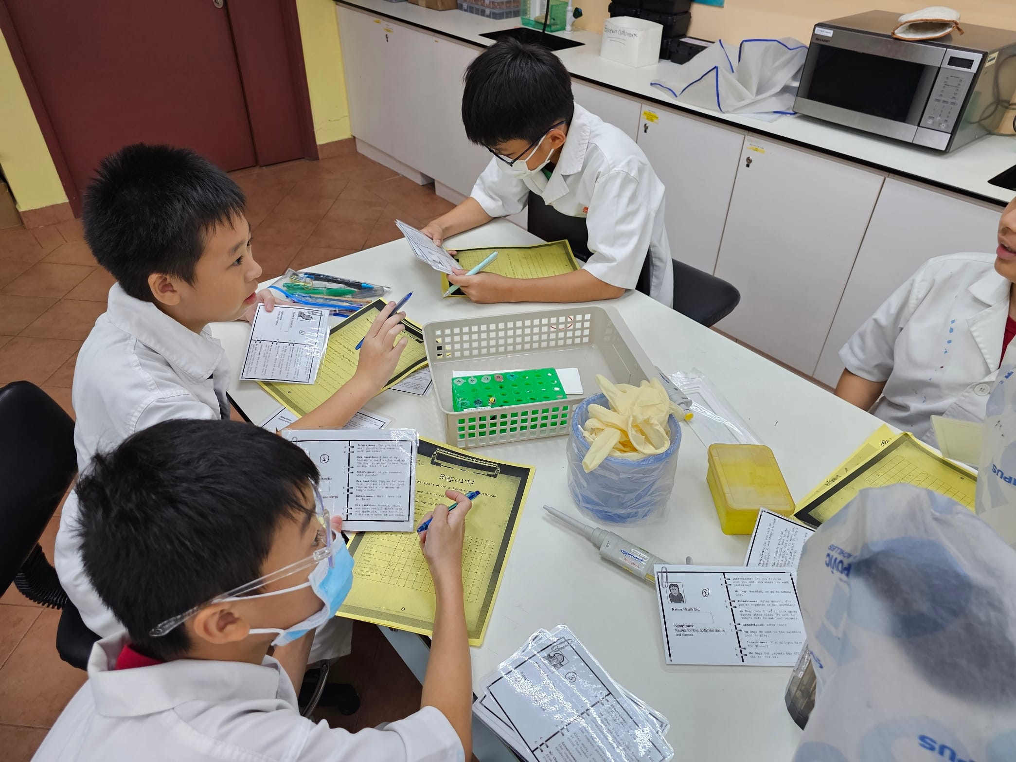 Students in lab coats practise how to formulate questions and design experiment protocols